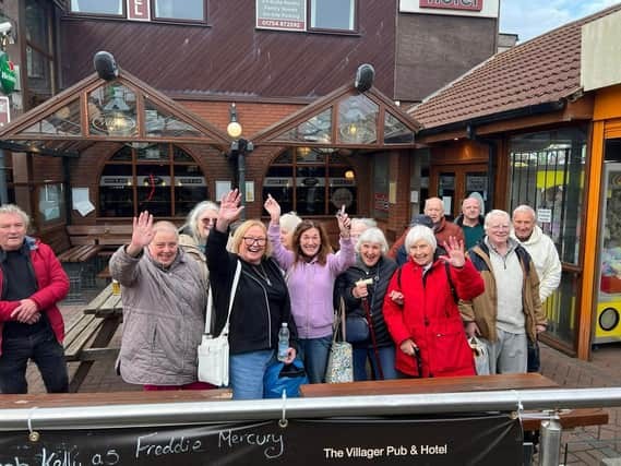 A group of people smiling and waving at the camera