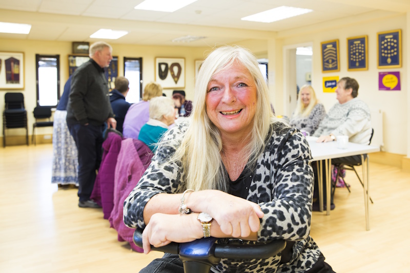 A woman smiles at the camera with a group at in the background