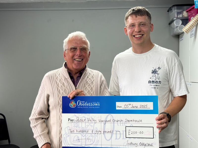 An Oddfellows and foodbank charity representative stood holding a big charity cheque