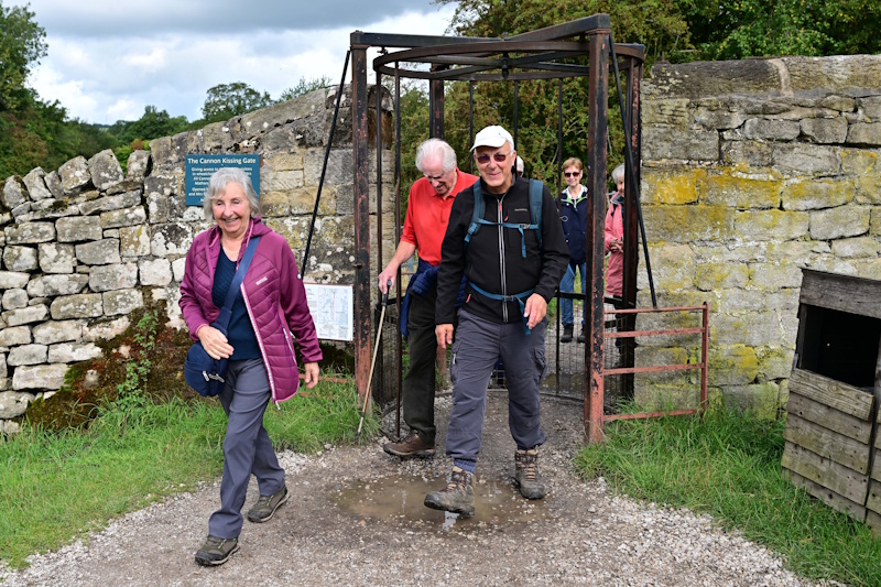 A group of people on a walk, passing through a gate while smiling